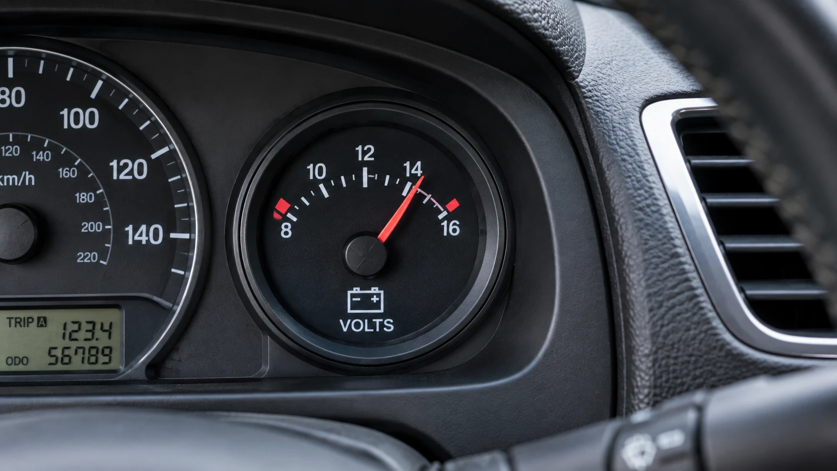 Automotive voltage gauge installed in a car dashboard showing a 14 volt reading